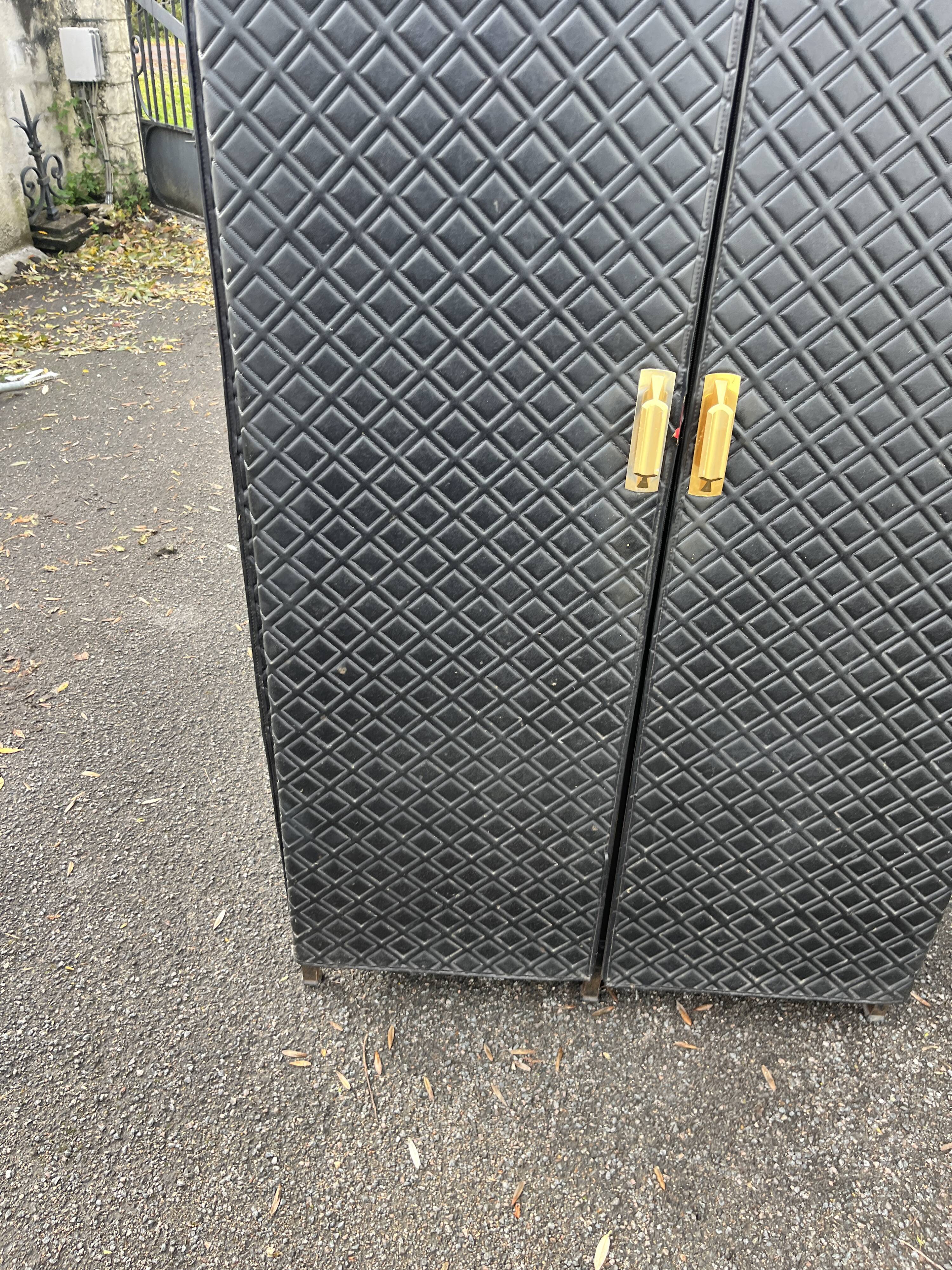 Contemporary wardrobe in black faux leather with diamond pattern and gold handles.