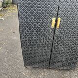 Contemporary wardrobe in black faux leather with diamond pattern and gold handles.