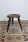Antique tripod stool made of turned wood.