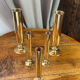Set of candlesticks and tubular vases in solid brass.