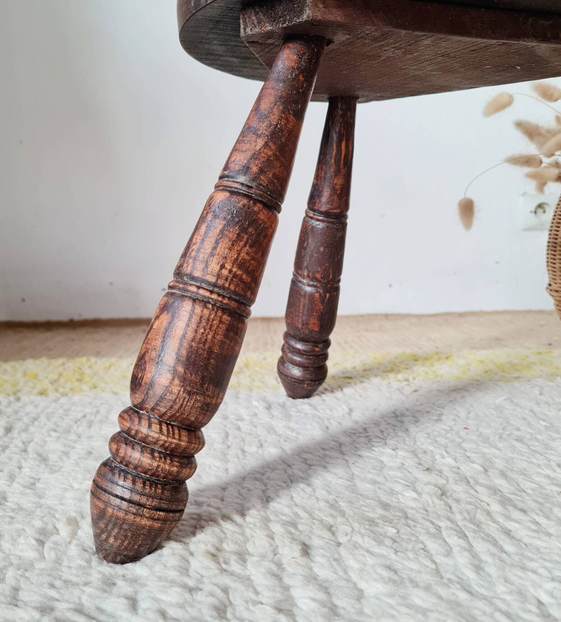 Small brutalist tripod stool made of turned wood.