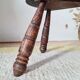 Small brutalist tripod stool made of turned wood.