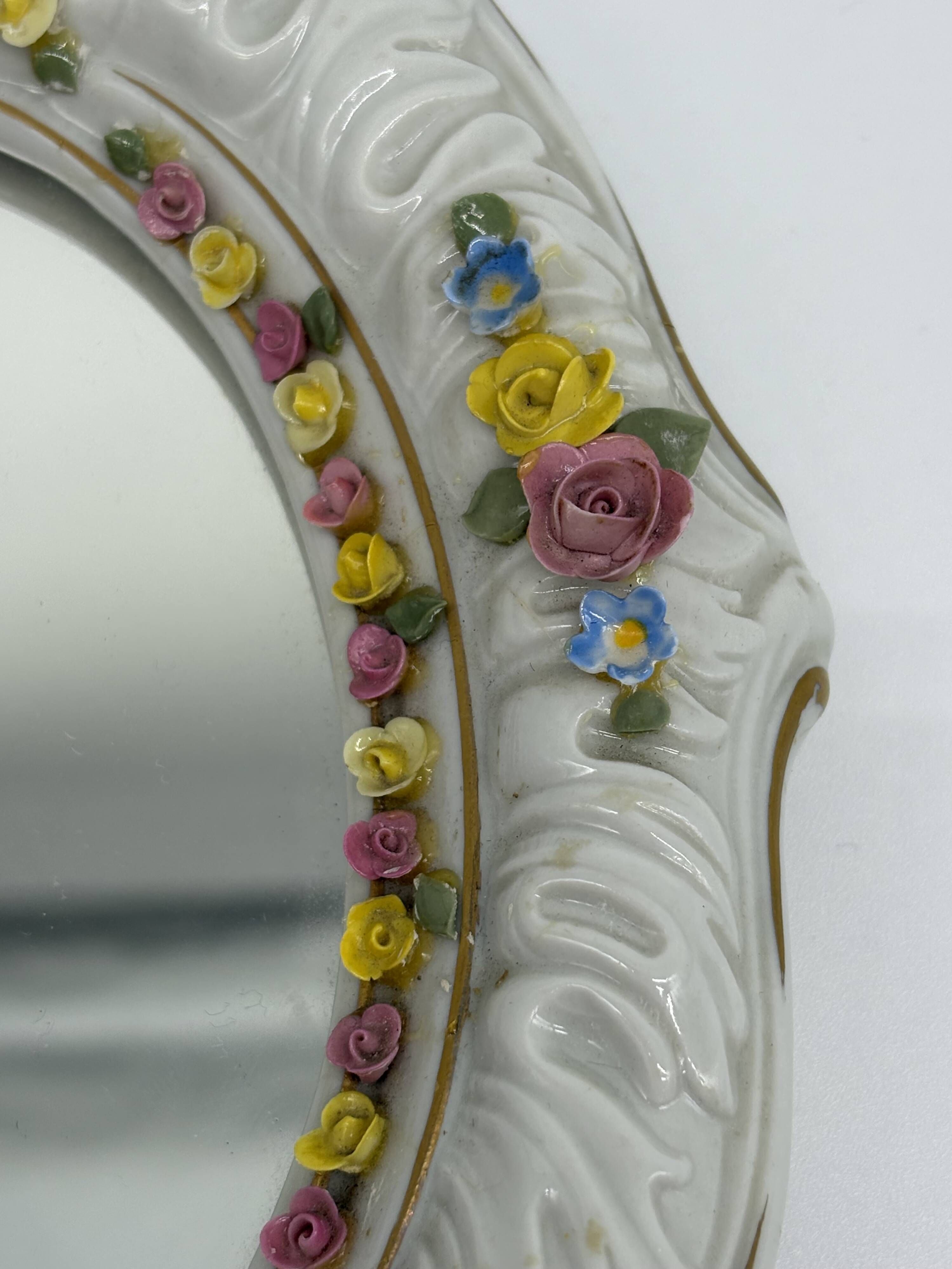 Antique porcelain mirror from Dresden with relief flowers and rococo decoration.