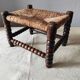 Antique wooden turned spool footrest with straw.