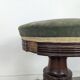 Green velvet piano stool with a turned leg.