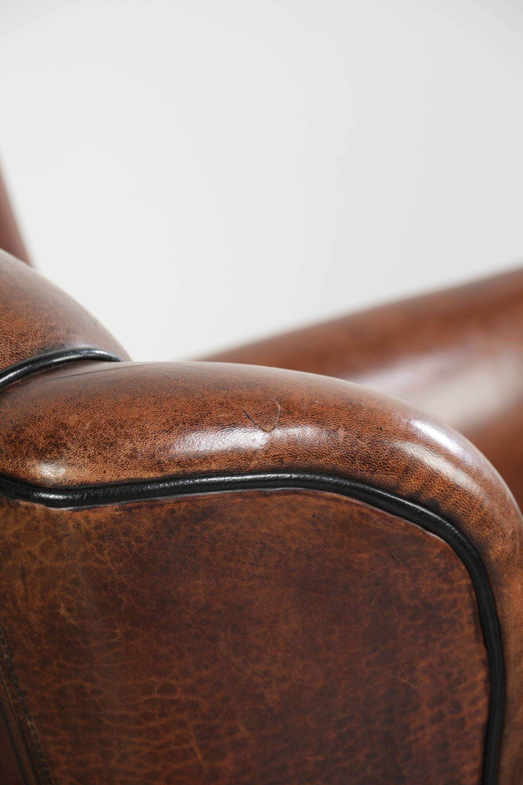Fauteuil en peau de mouton confortable au design unique, fini avec un passepoil noir.