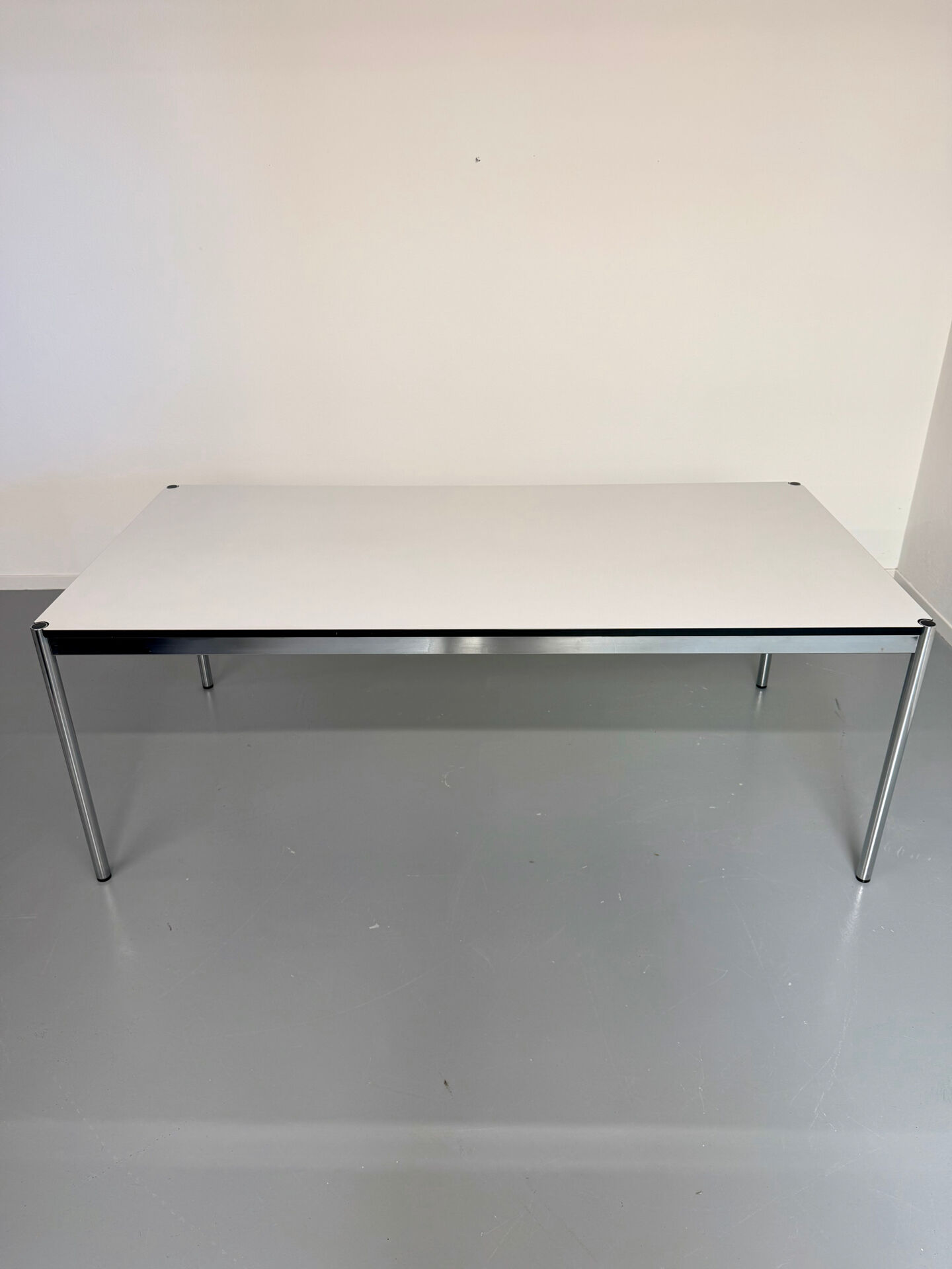 Large table design USM Haller with a white top and chrome structure.