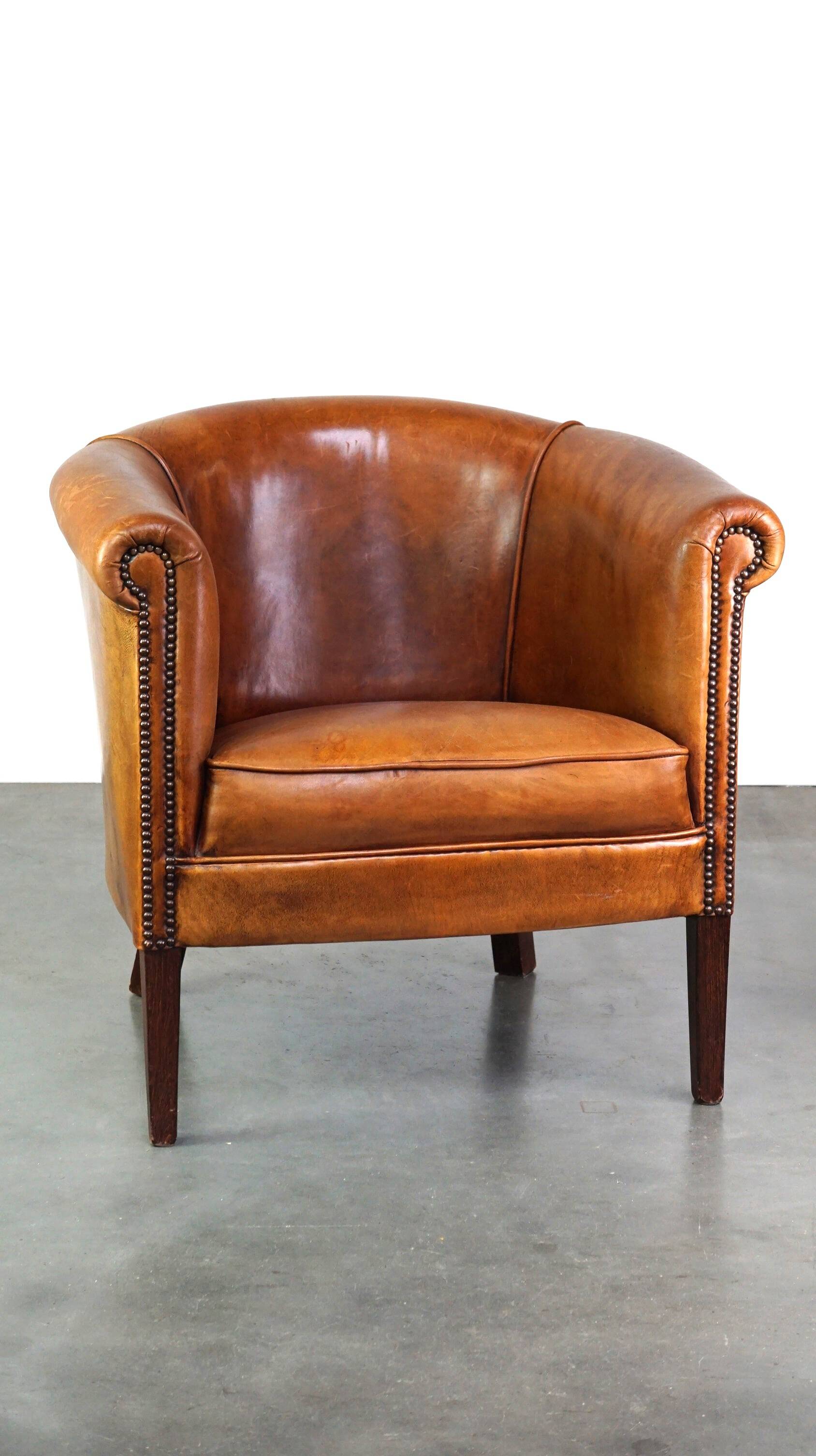 Neat and subtle sheepskin club chair, finished with decorative studs and a fixed seat cushion