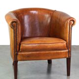 Neat and subtle sheepskin club chair, finished with decorative studs and a fixed seat cushion