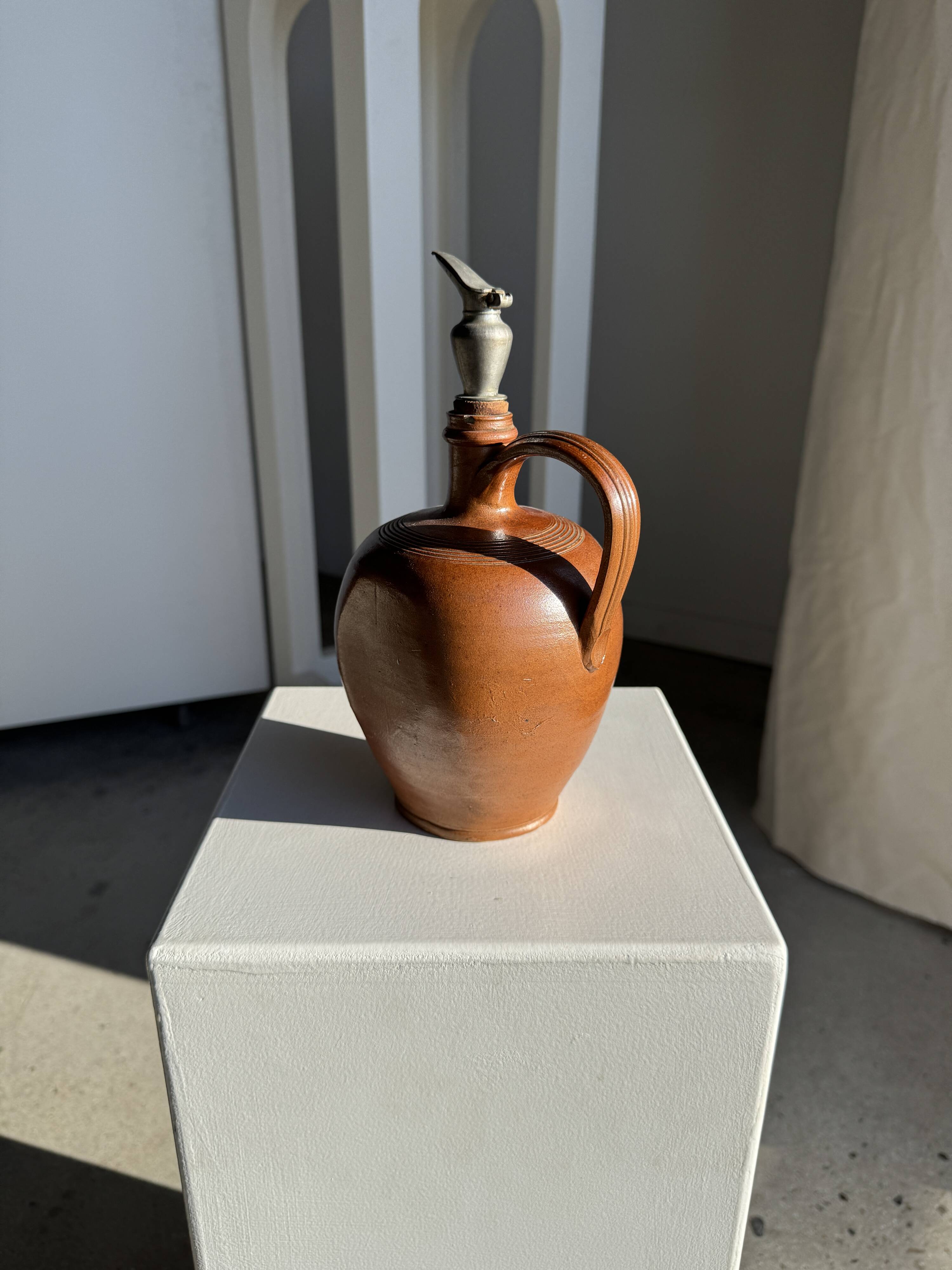 Ancient stoneware jug with a pewter spout.