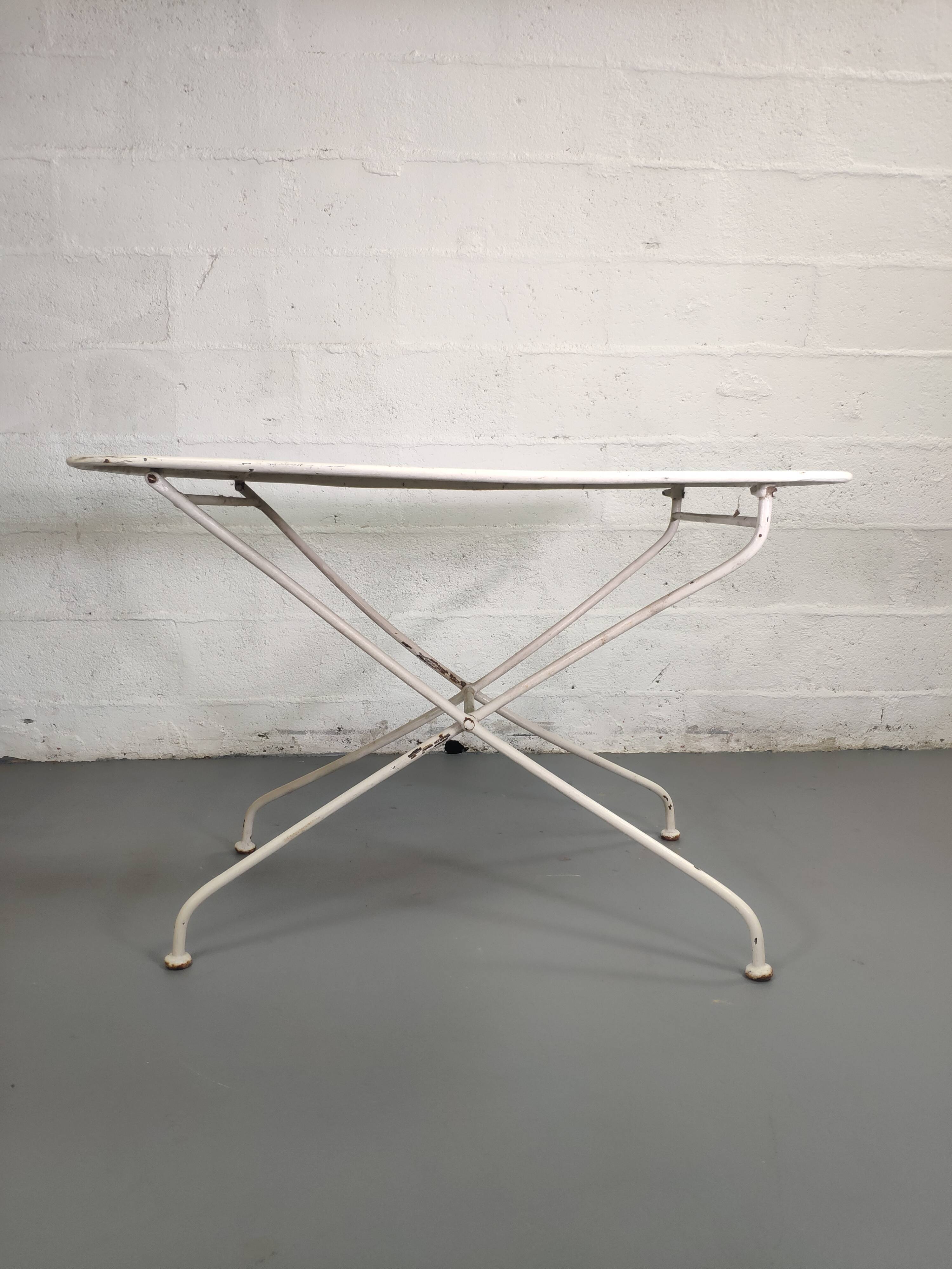 Old folding garden table in white wrought iron
