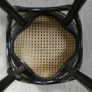 Curved wooden bar stool with a caned seat.