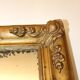 Miroir rectangulaire en bois doré à décor en relief de fleurs.