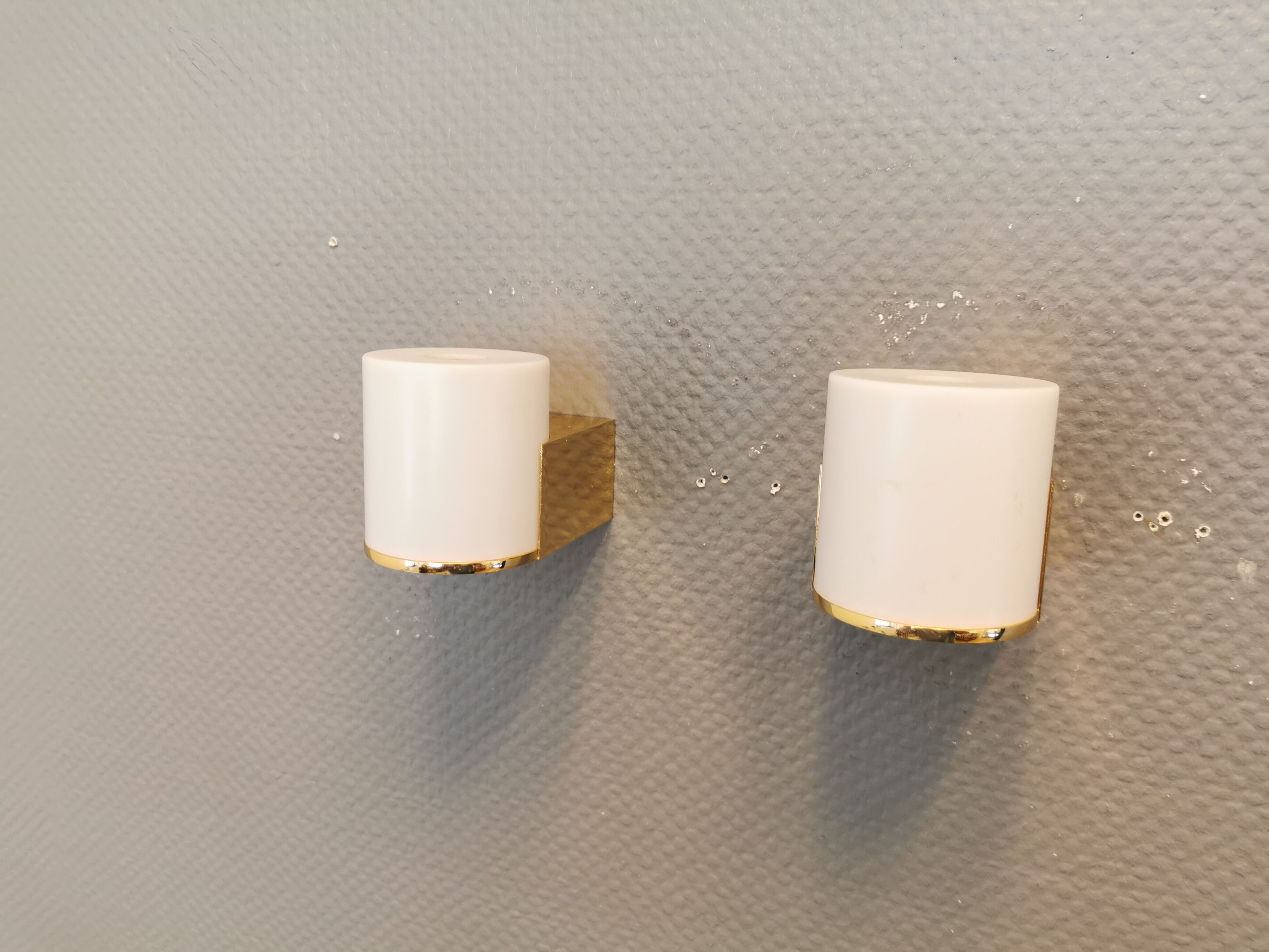 Wall lamps with milky white acrylic plastic shades and solid brass bases