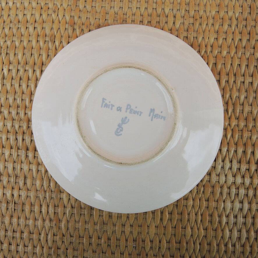 Old ceramic saucer decorated with hand-painted flowers.