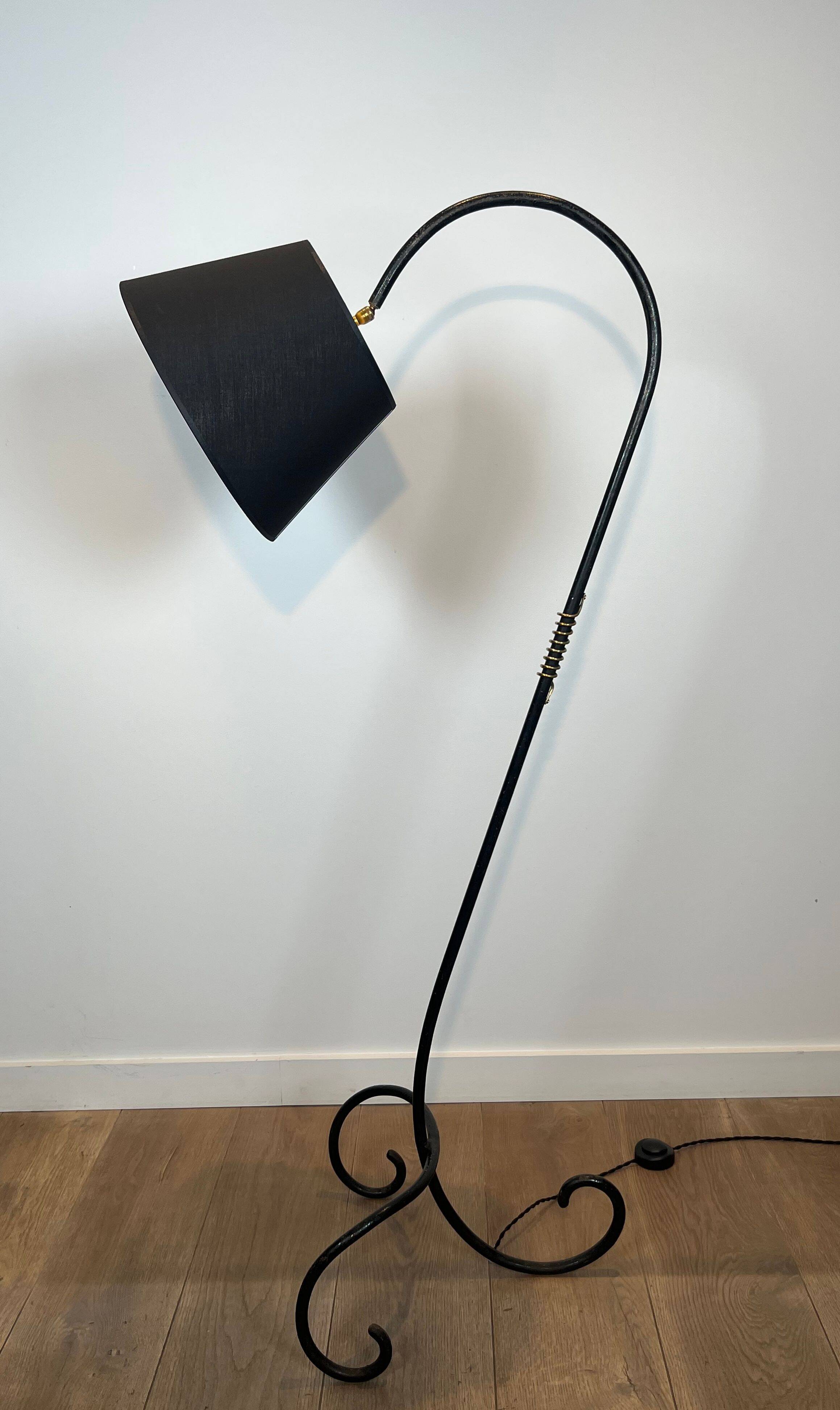 Design floor lamp in black lacquered metal and brass.