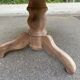 Round extendable dining table stripped in solid raw walnut with a central leg.