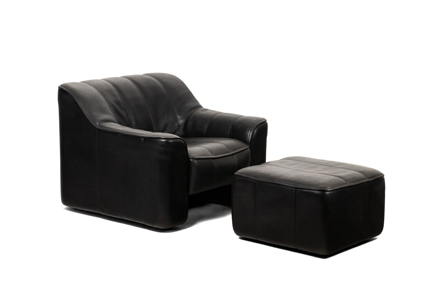 Maison De Sede. Armchair and its ottoman in black leather. 1970s.