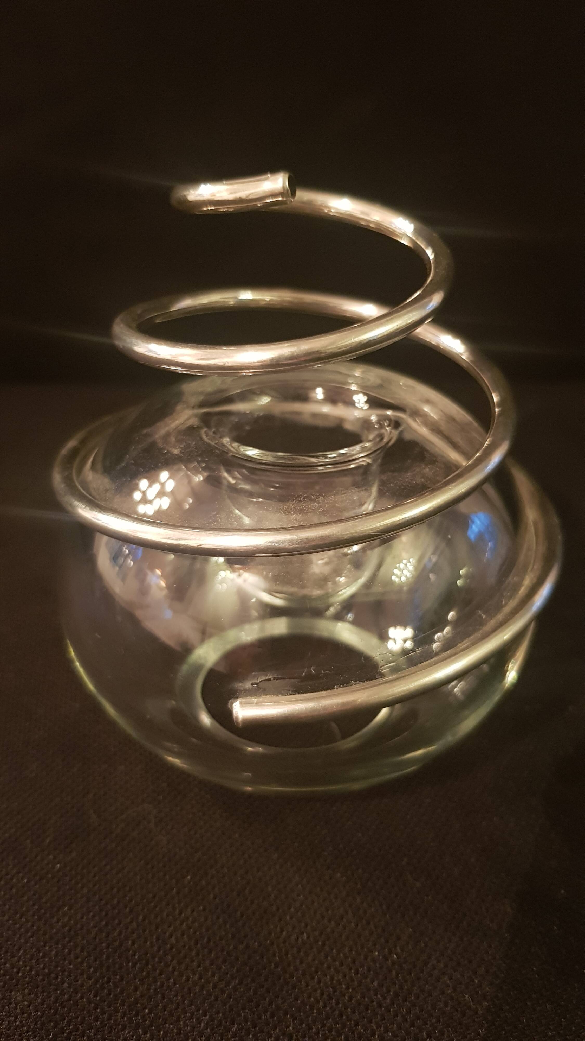 Round glass candle holder with silver-plated metal spiral.