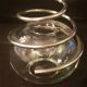 Round glass candle holder with silver-plated metal spiral.