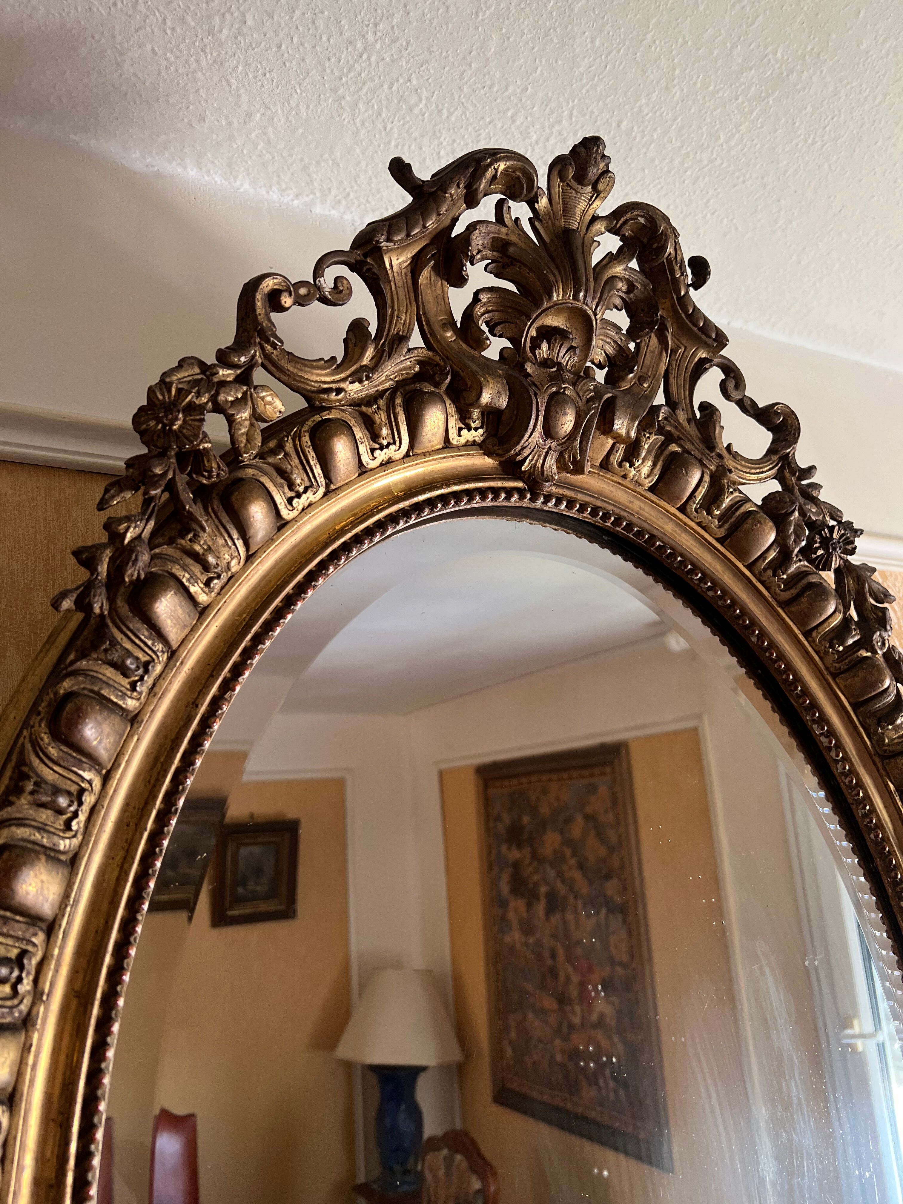 Antique oval mirror in gilded stucco with ornamentation