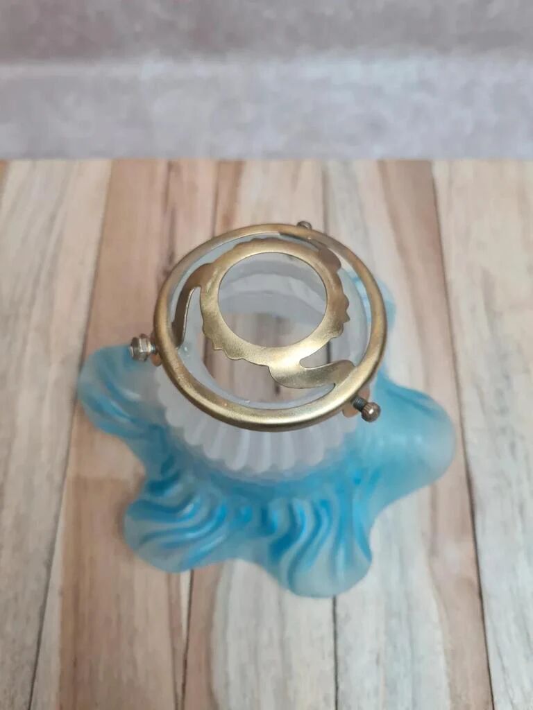 An antique lampshade in frosted glass with delicate blue edges.