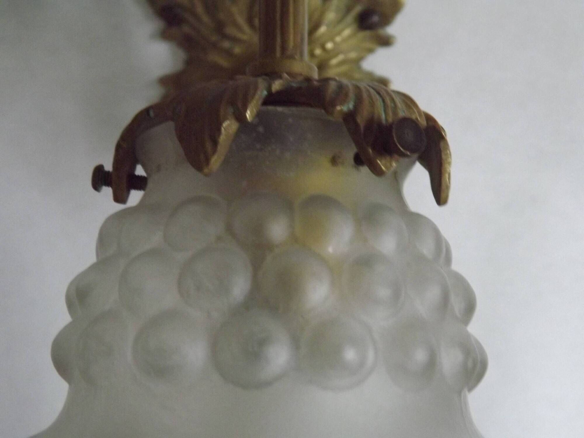 Simple wall sconce in French Art Nouveau bronze with a white glass shade featuring patterns.