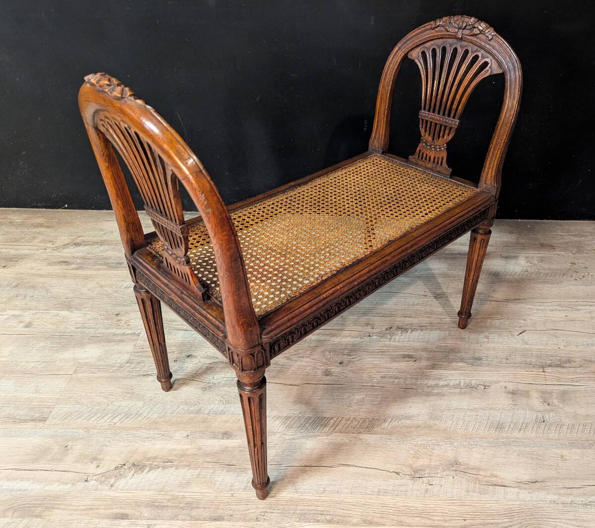 Louis XVI bench in walnut with cane seating.