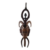 A large Senufo mask made of colored wood, decorated with an anthropomorphic figure