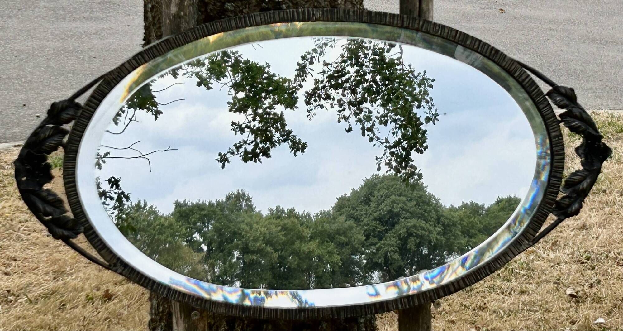 Bevelled oval mirror, richly crafted Art Deco wrought iron.