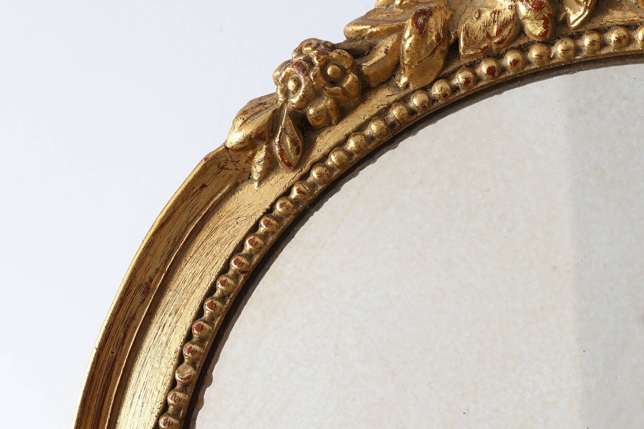 Oval giltwood mirror with rococo-style floral crest, mid-20th century