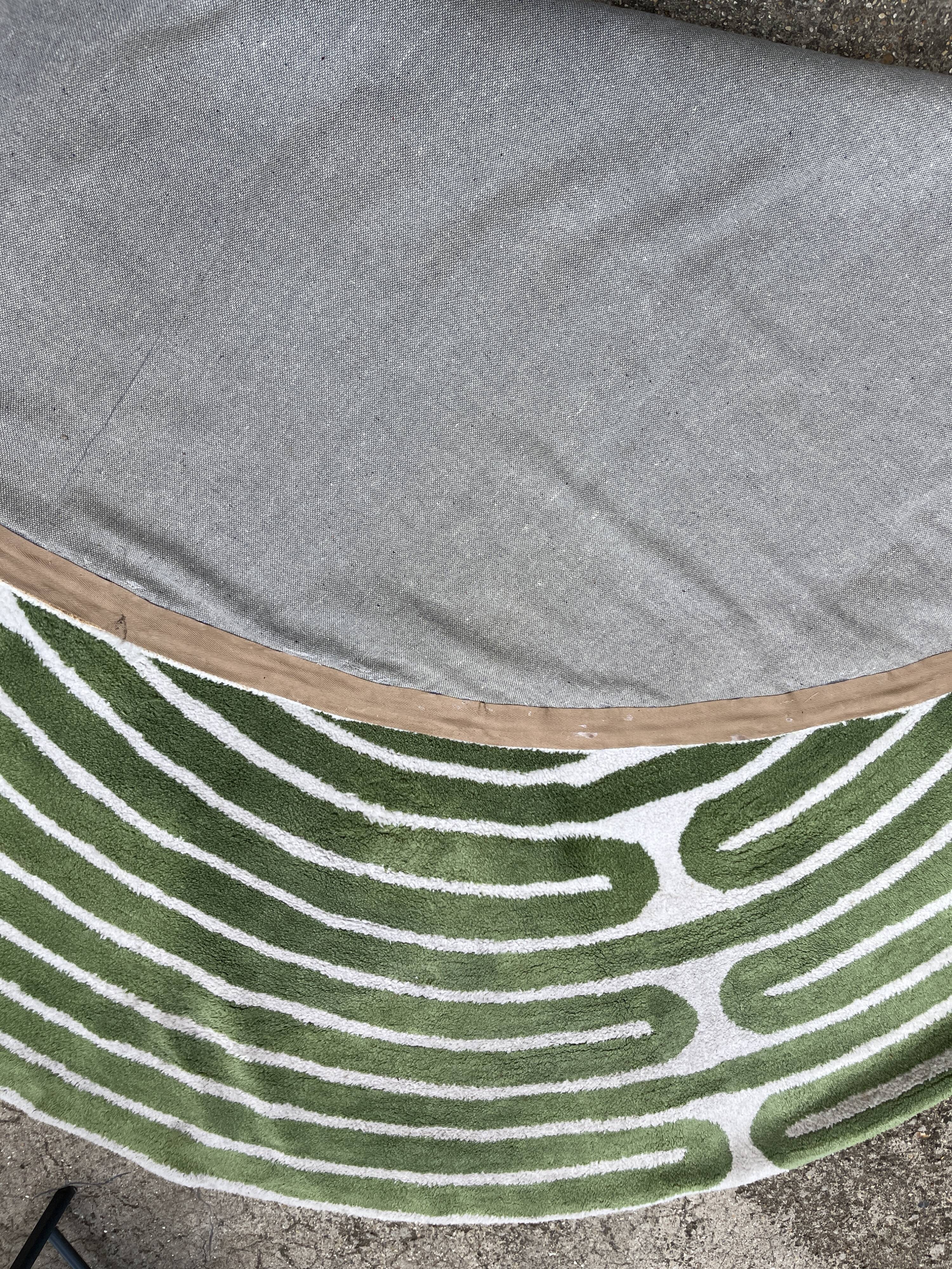 Circular rug with green decor on a cream background from the Labyrinth.