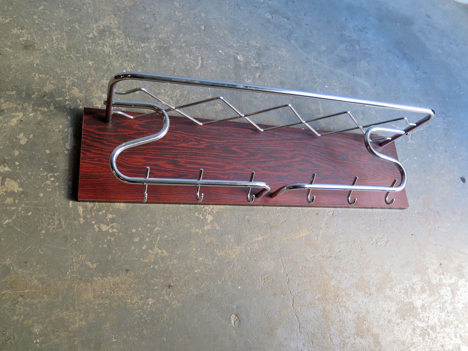 Chrome metal patere in a wooden support panel coat veneer.