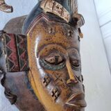 A large Senufo mask made of colored wood, decorated with an anthropomorphic figure