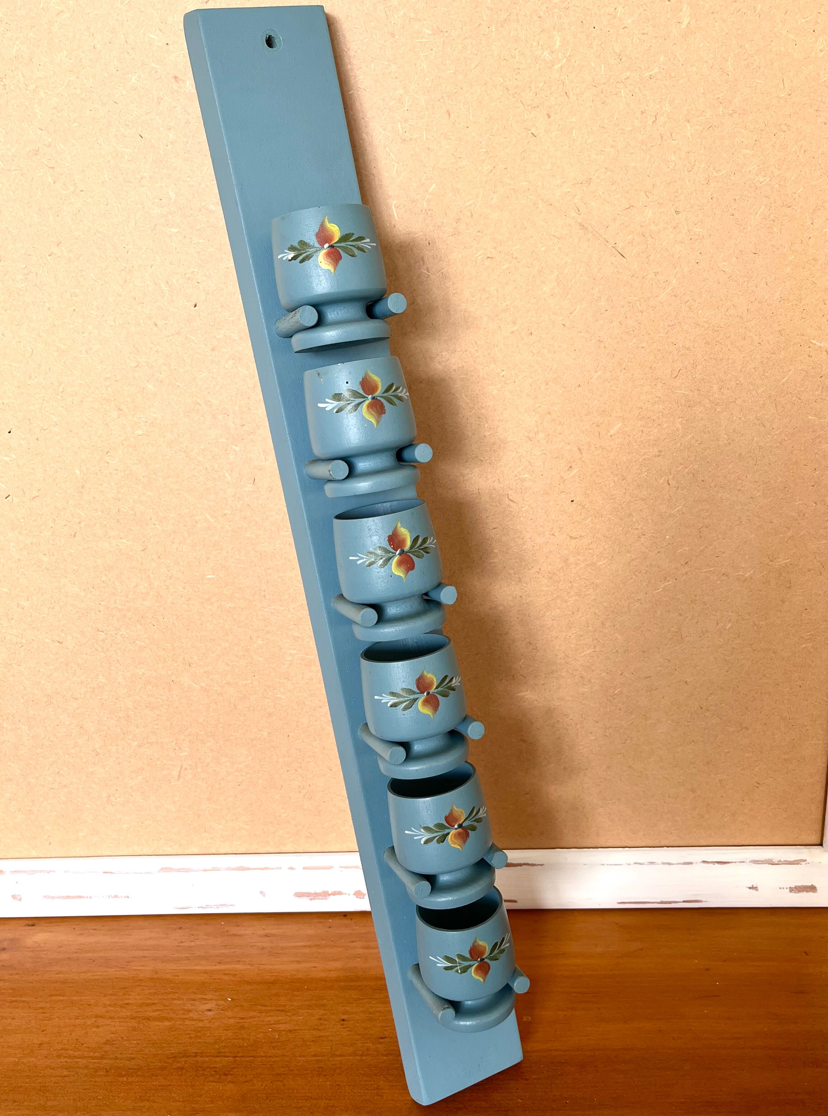 6 vintage egg cups on a wall shelf
