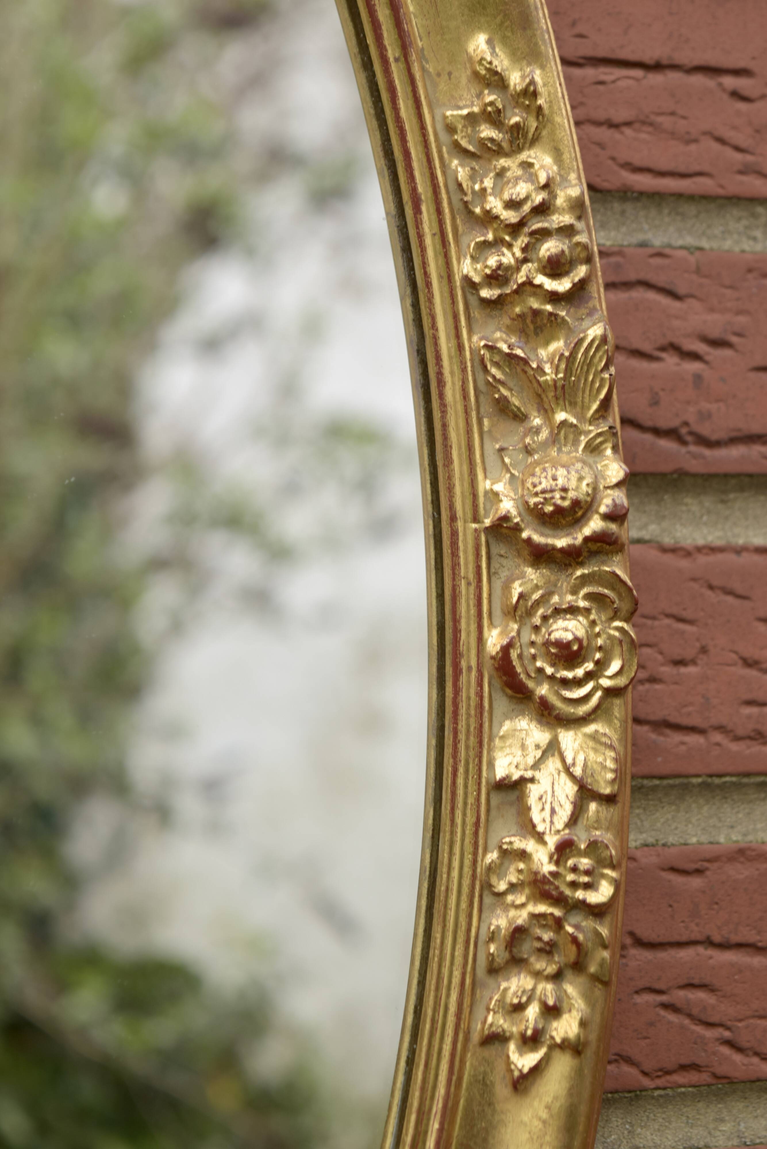 Old large oval wall mirror in golden resin
