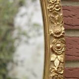 Old large oval wall mirror in golden resin