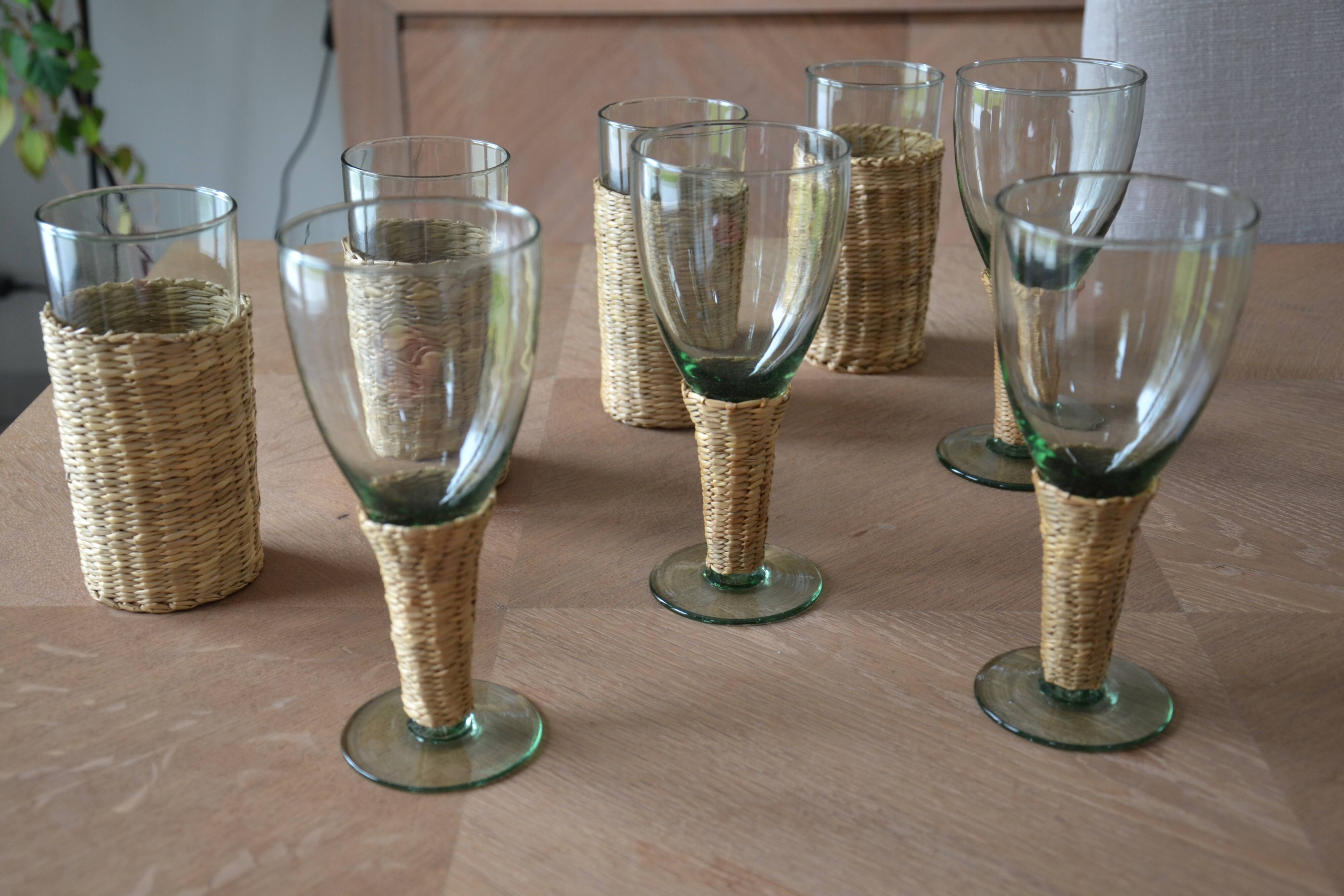 Four stemmed glasses surrounded by rattan.