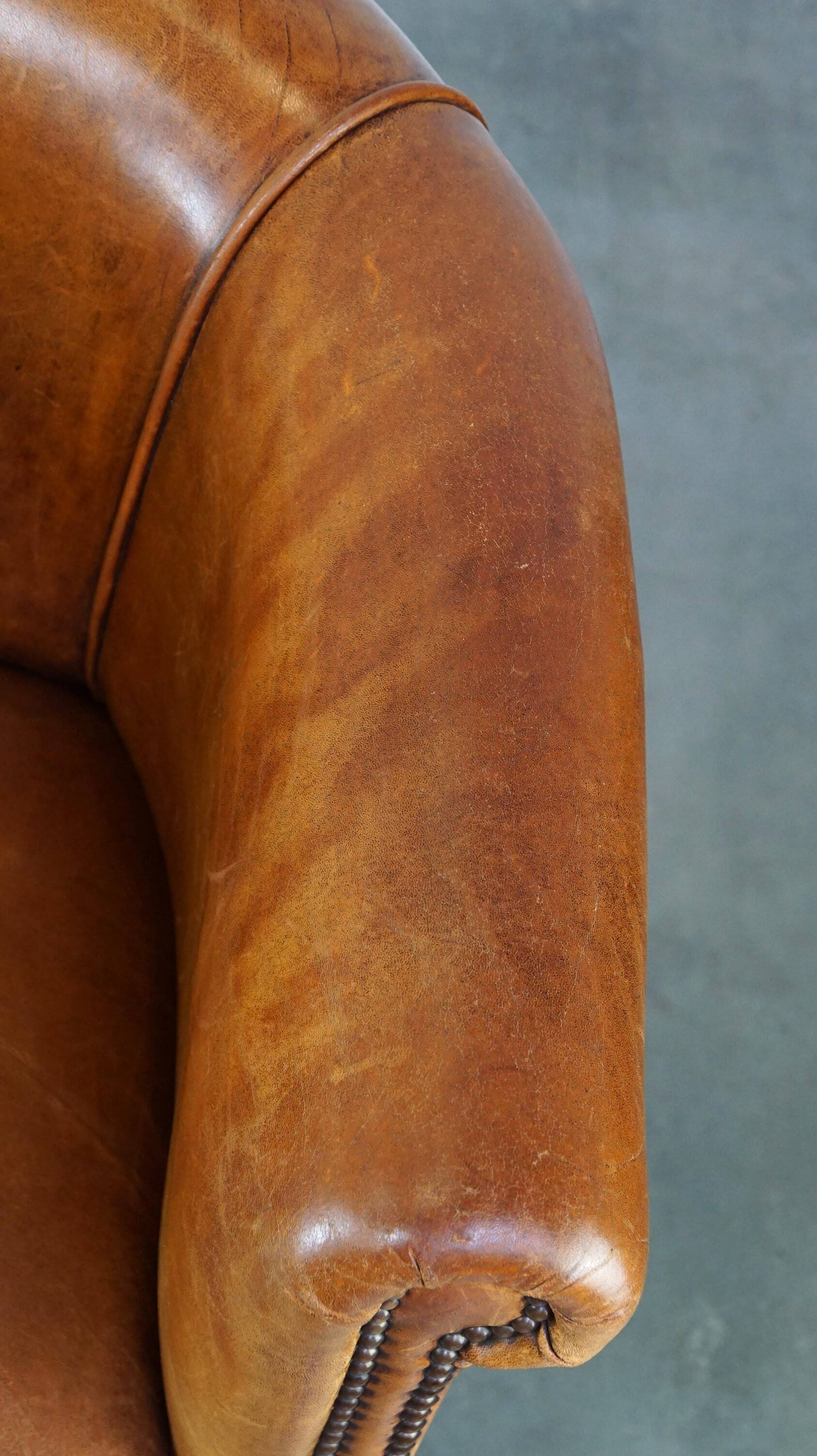 Neat and subtle sheepskin club chair, finished with decorative studs and a fixed seat cushion