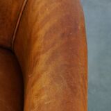 Neat and subtle sheepskin club chair, finished with decorative studs and a fixed seat cushion