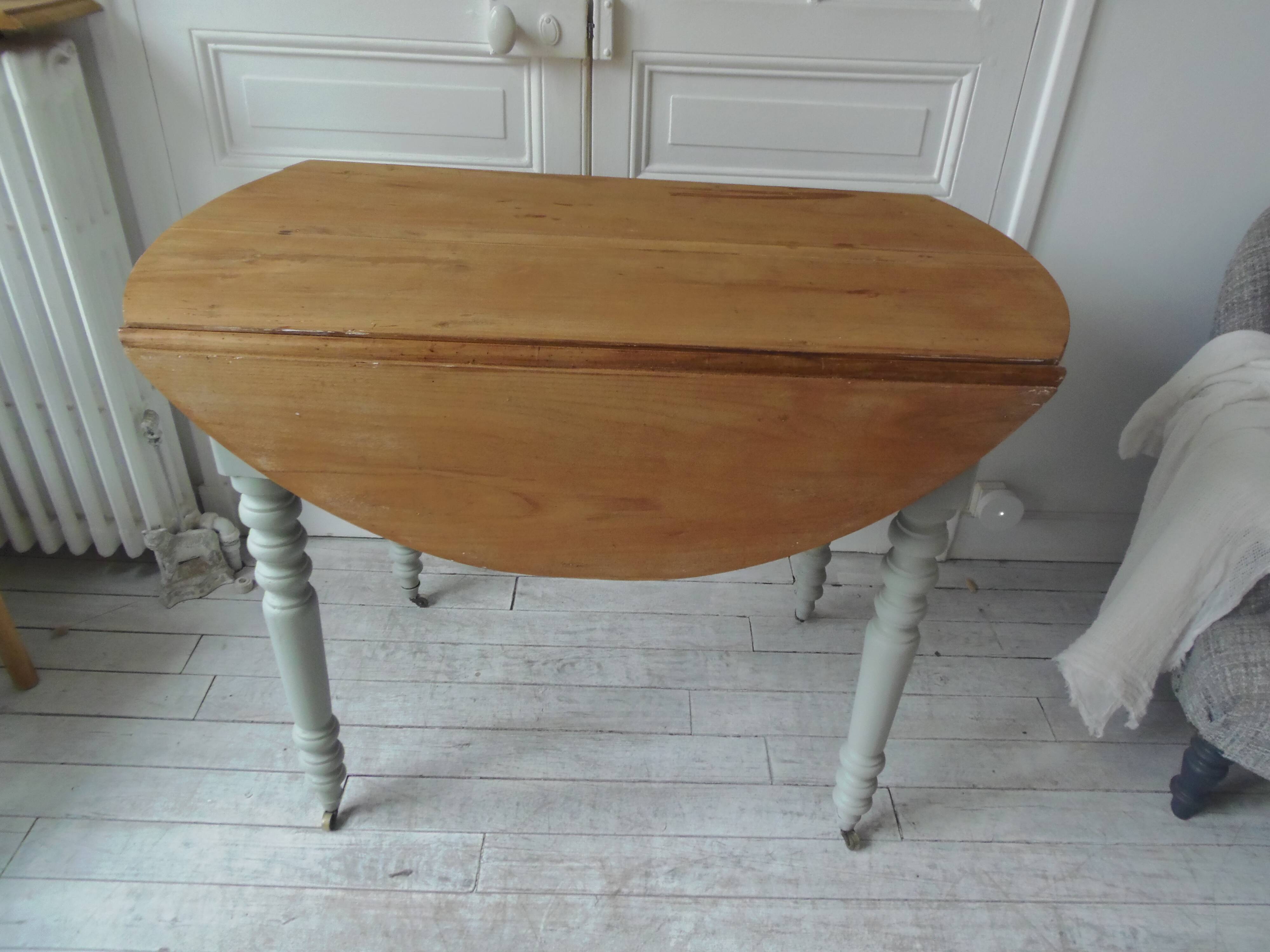 Raised walnut table with drop-leaf top, base on verdigris castors.