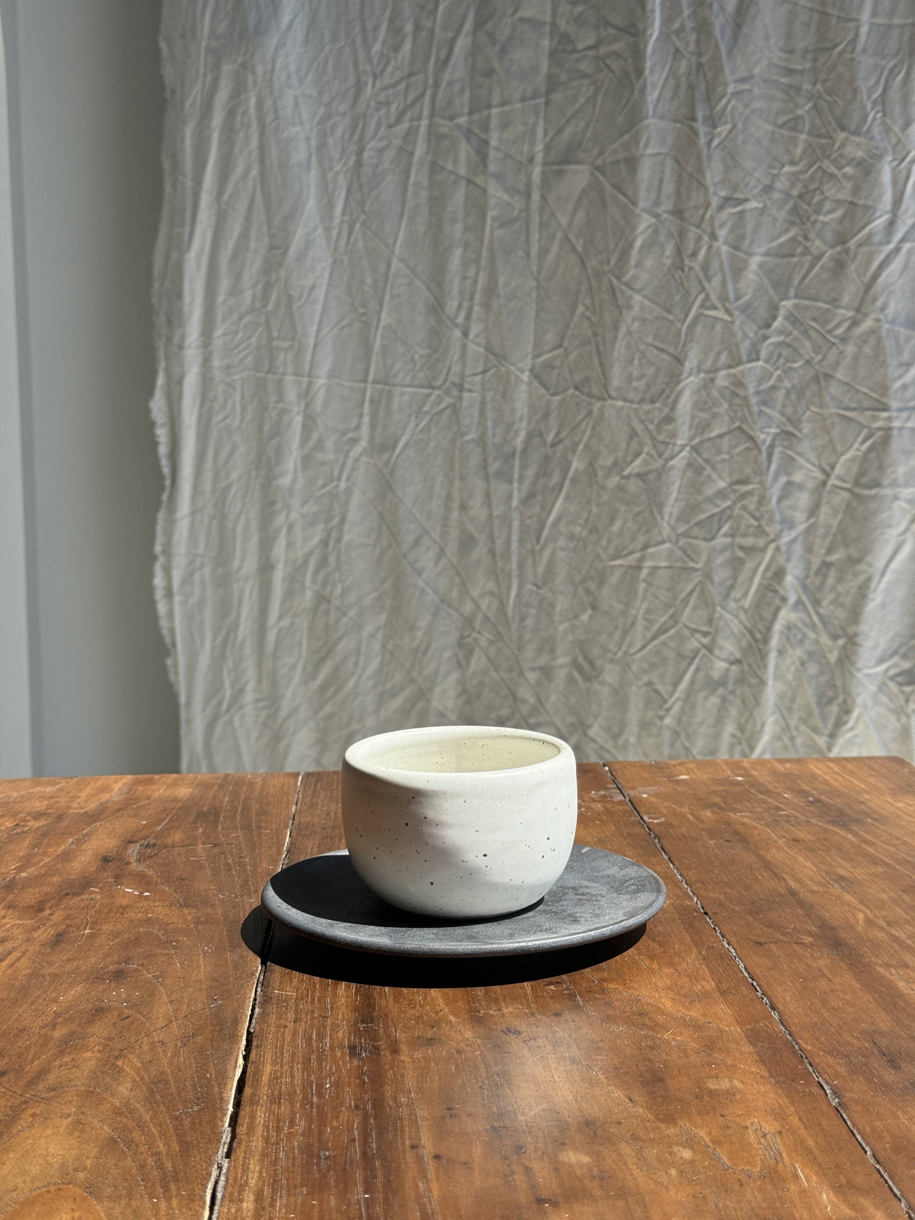 White Indonesian ceramic cup and gray saucer