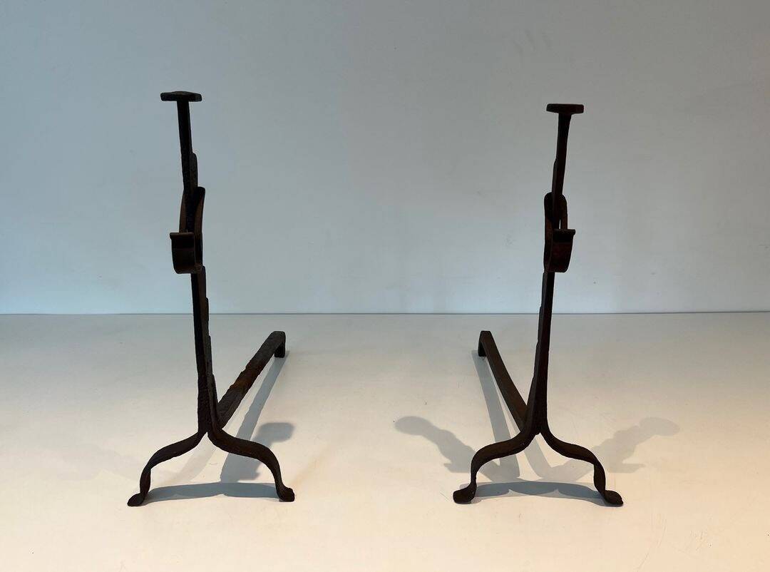 Pair of wrought iron andirons with adjustable supports and tripod feet.