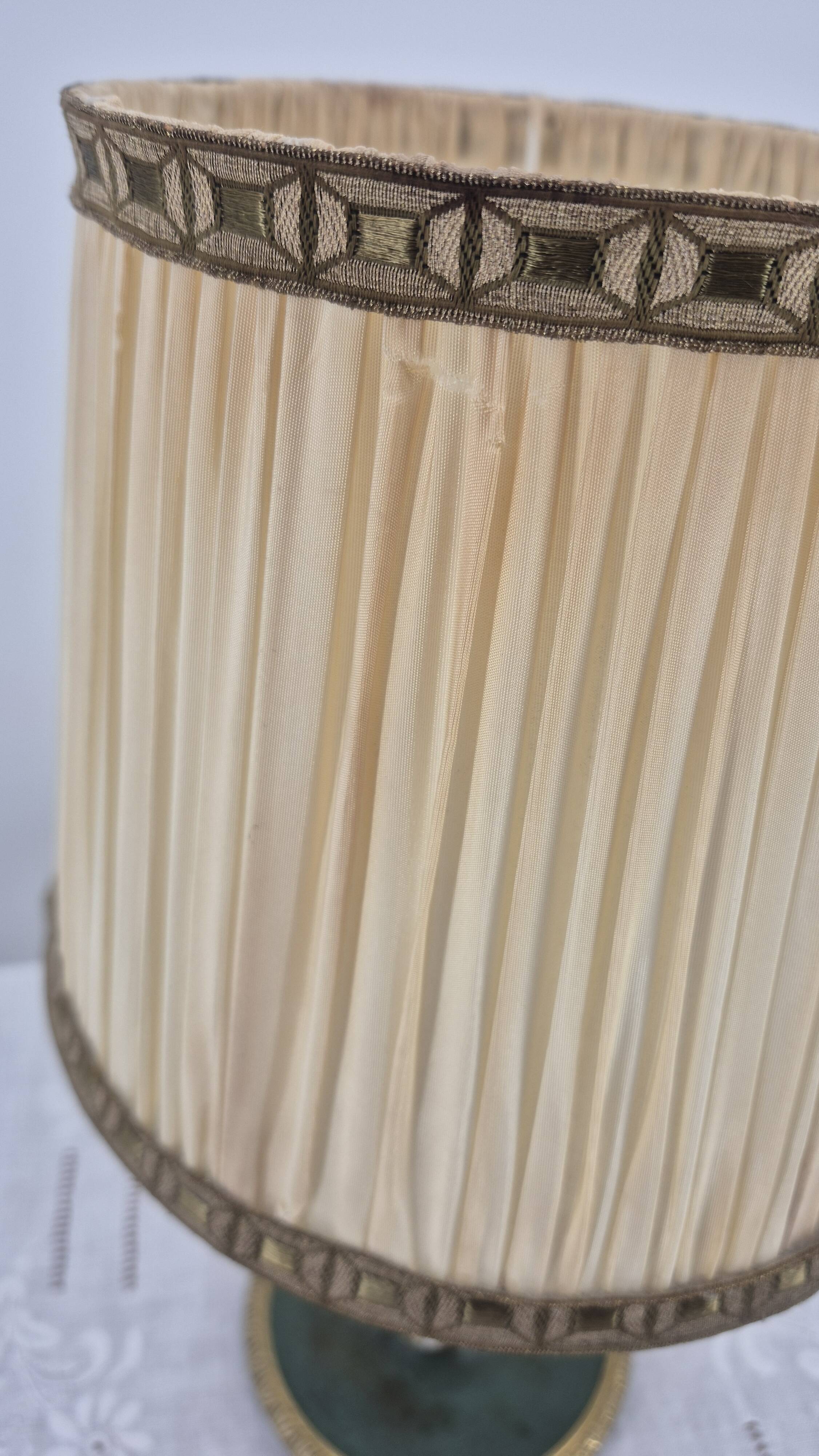Brass table lamp with green patina and empire-style fabric shade.