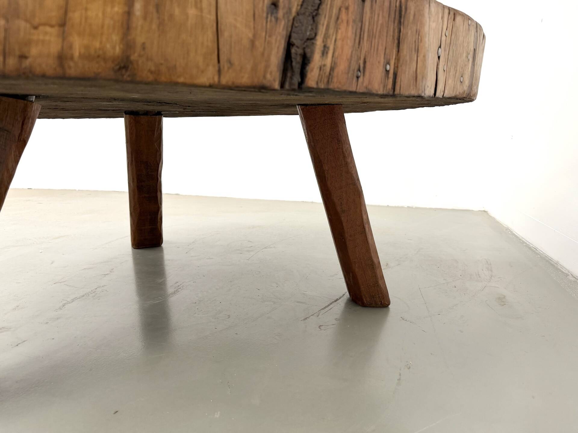 Brutalist coffee table in solid teak, monolithic slab, tripod base.