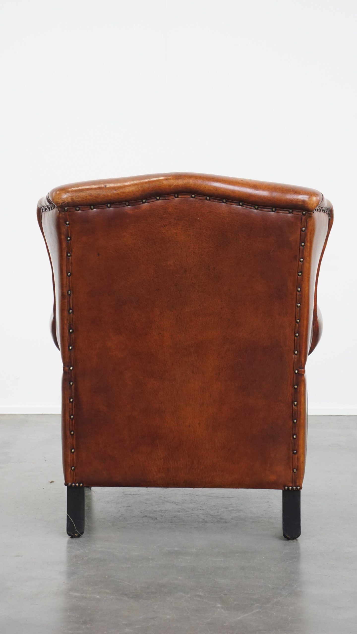 Sheepskin wingback armchair with stitching and black piping