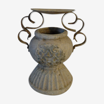 Ancient earthenware pot with sculptures on the sides and wrought iron cover