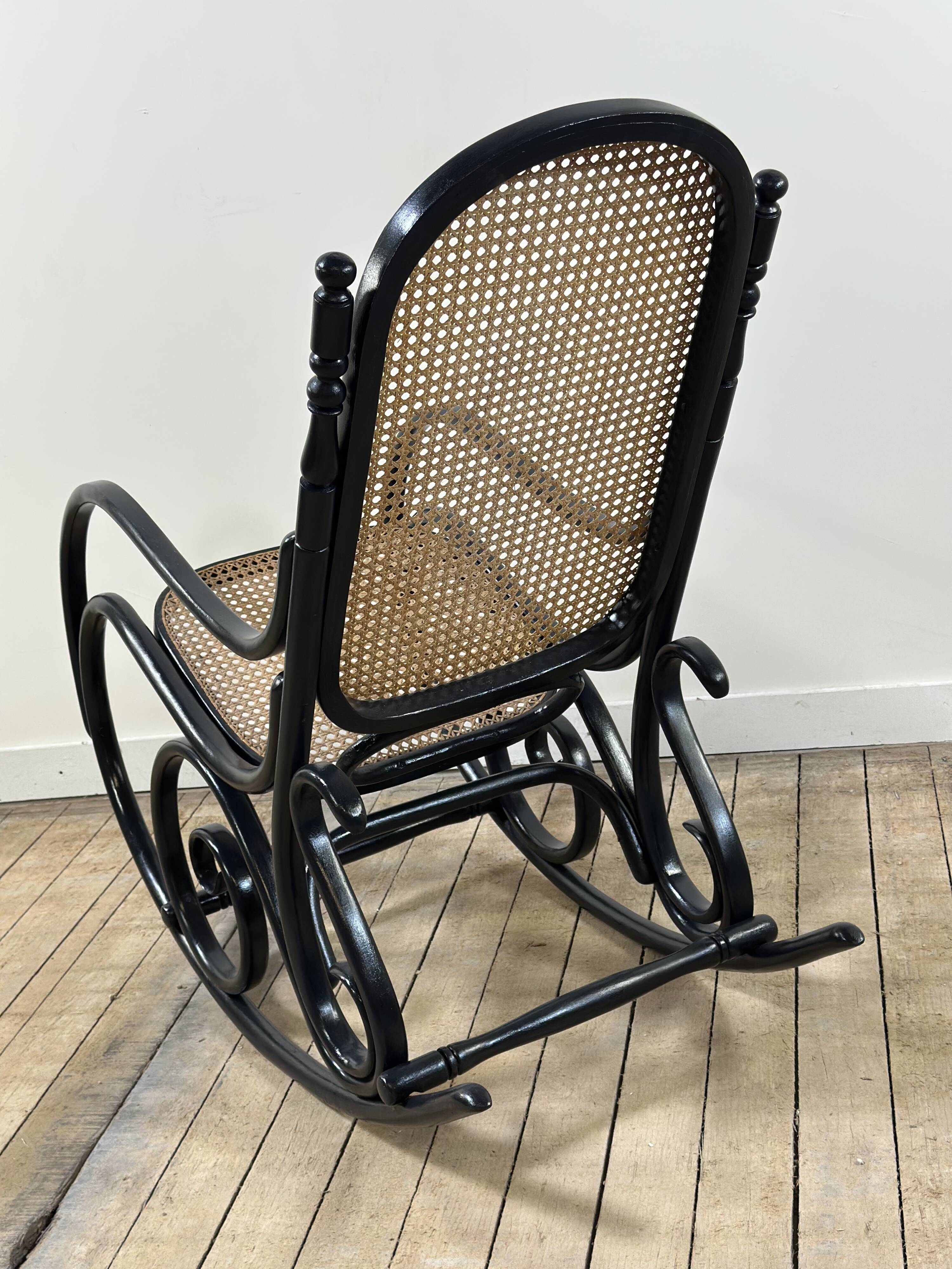 Rocking-chair en bois courbé noirci et cannage années 1900