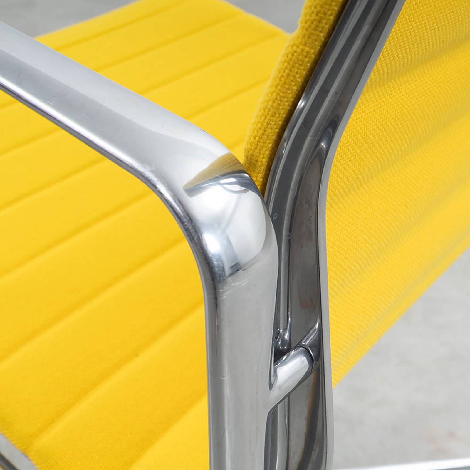 Fauteuil Aluminum Group EA107 de Charles et Ray Eames en tissu jaune.