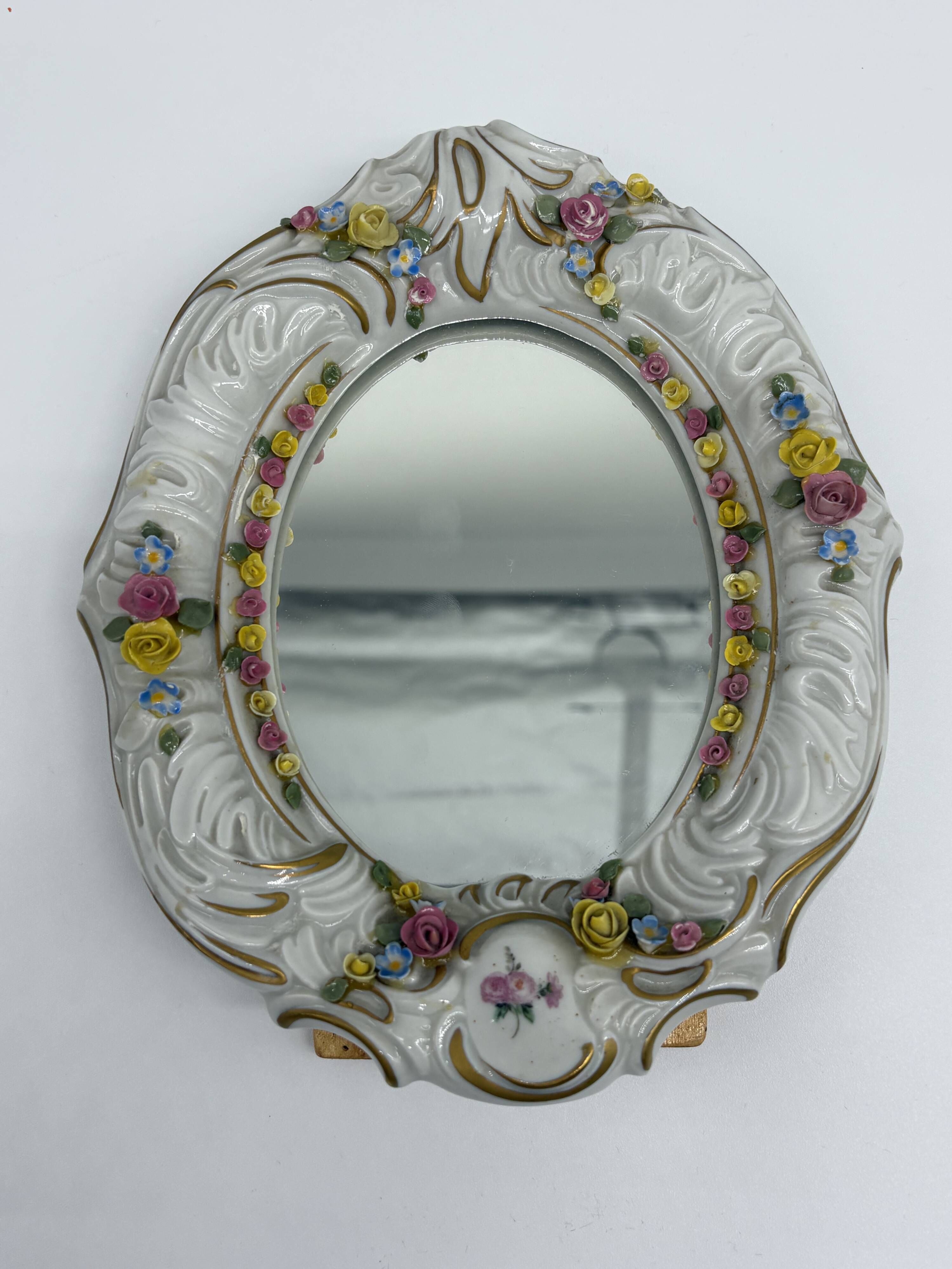 Antique porcelain mirror from Dresden with relief flowers and rococo decoration.